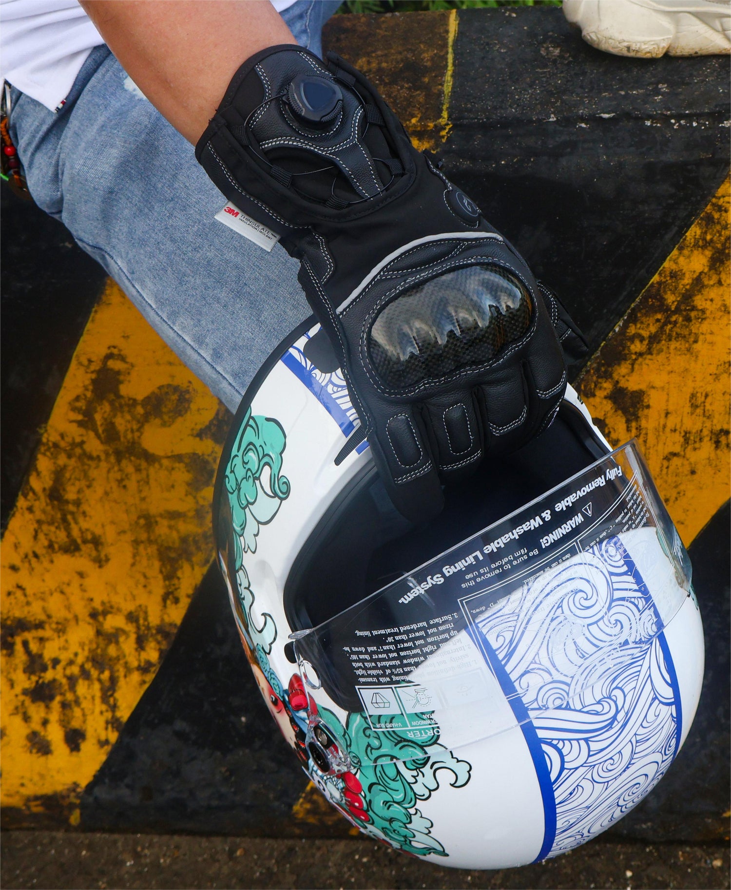A man wearing Onyx heated motorcycle gloves and holding a motorcycle helmet.