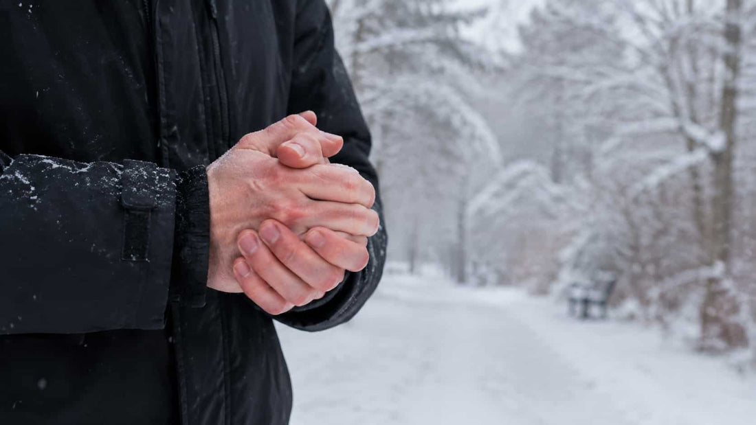 Person holding bare hands together in cold snowy weather