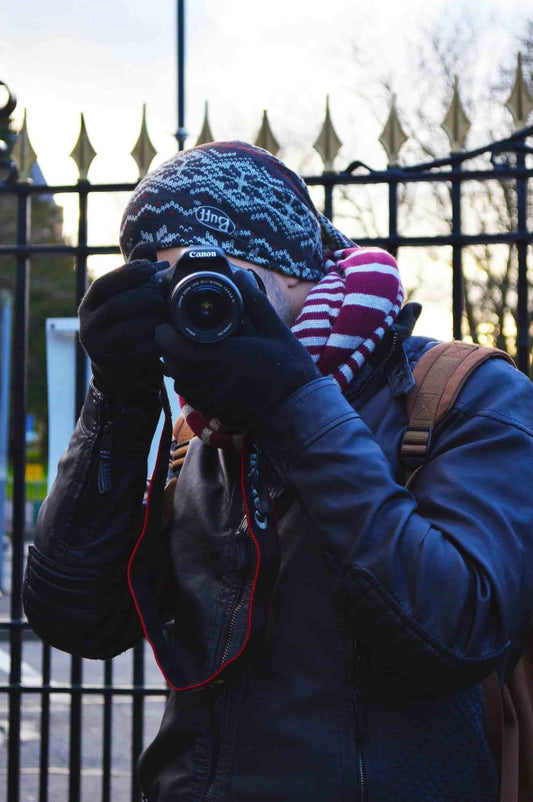 Winter photographer wearing thin heated gloves while adjusting camera controls in snowy conditions