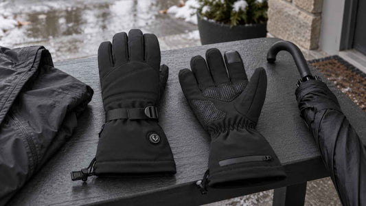 WinterGlow heated gloves beside a rain jacket and umbrella after light winter rain
