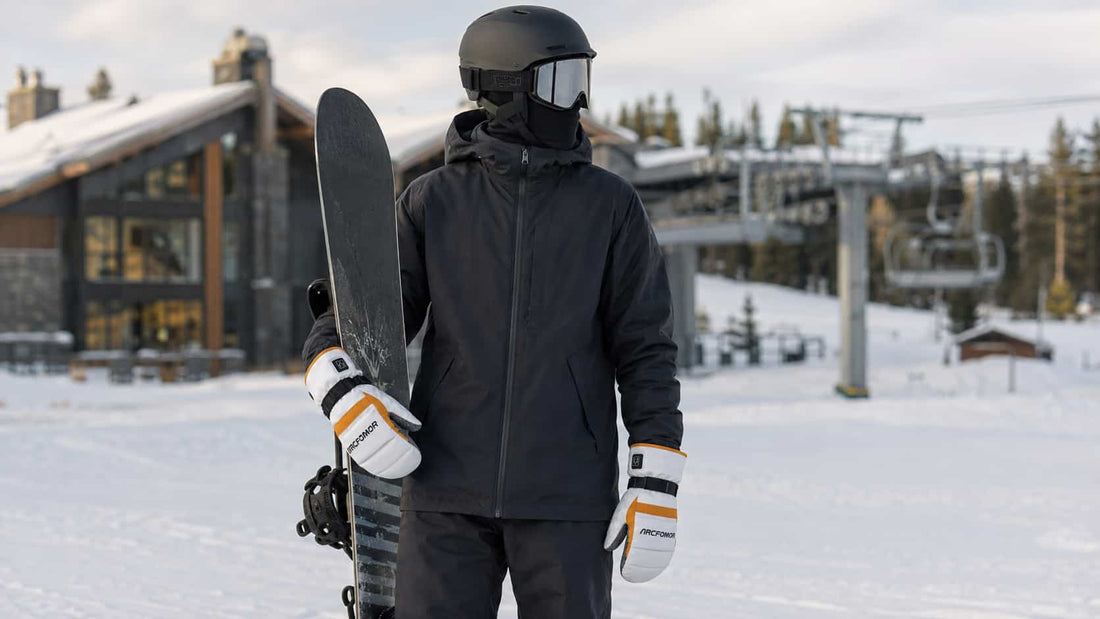 Snowboarder wearing Toboggan heated mittens while carrying a board at a winter resort