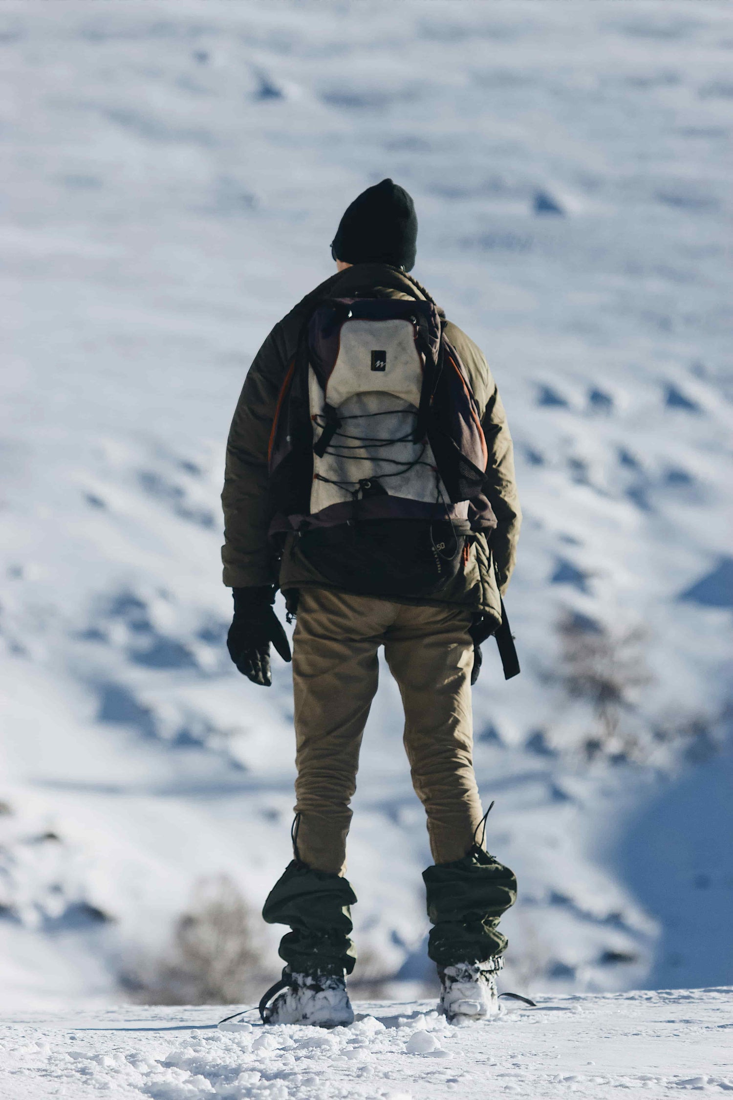 A man wearing Arc'teryx heated gloves hiking in the wilderness in winter