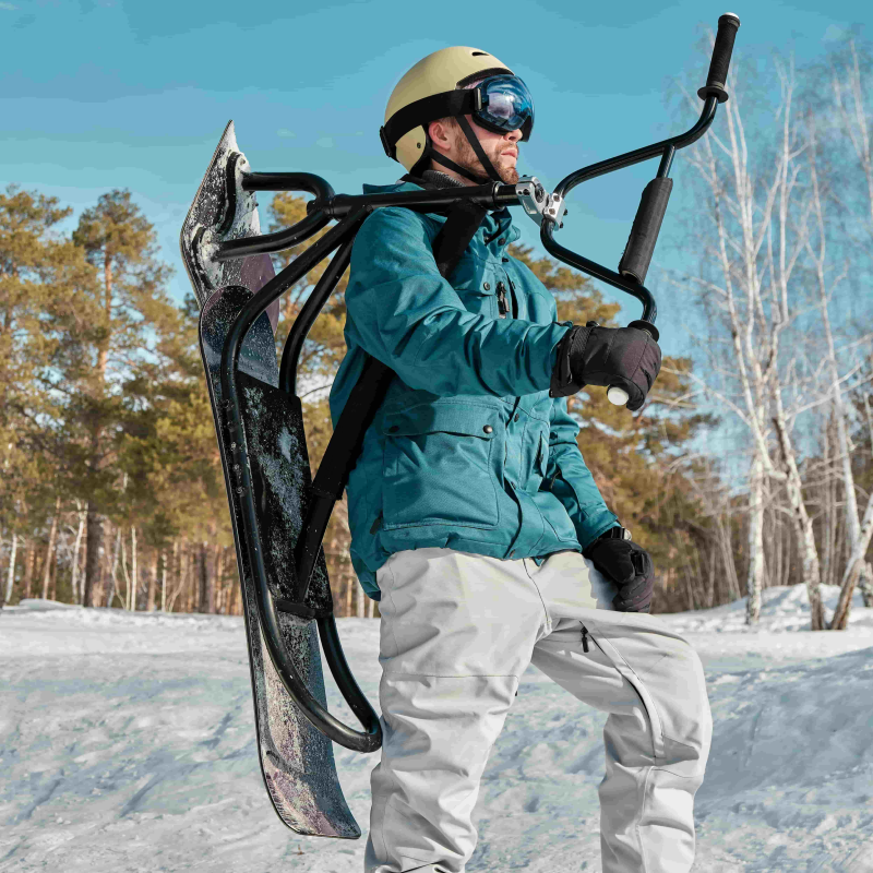 A man in a ski suit, wearing Arcformor heated ski gloves, stands in the snow