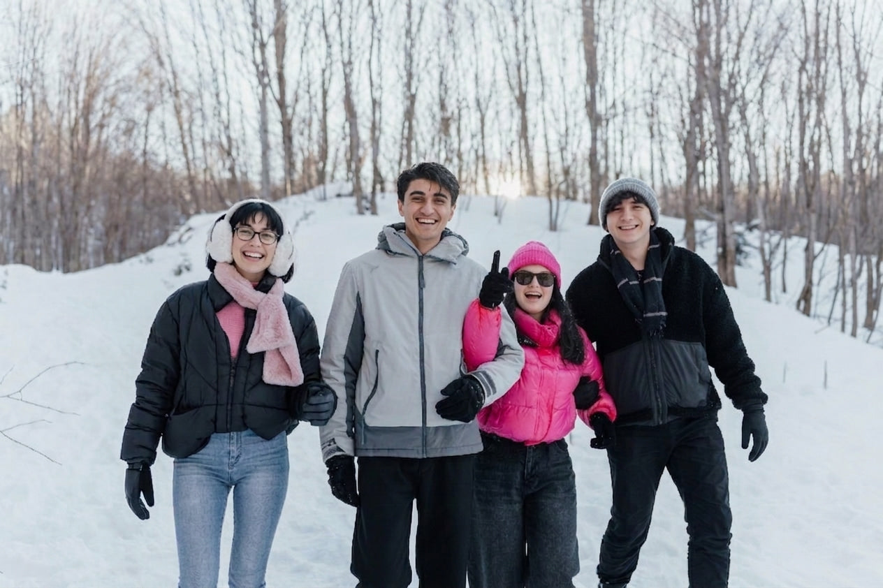Happy friends wearing winter apparel and Arcfomor rechargeable heated gloves in snowy outdoors for winter gift guide