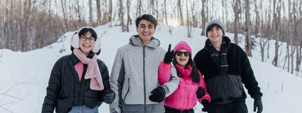 Happy friends wearing winter apparel and Arcfomor rechargeable heated gloves in snowy outdoors for winter gift guide