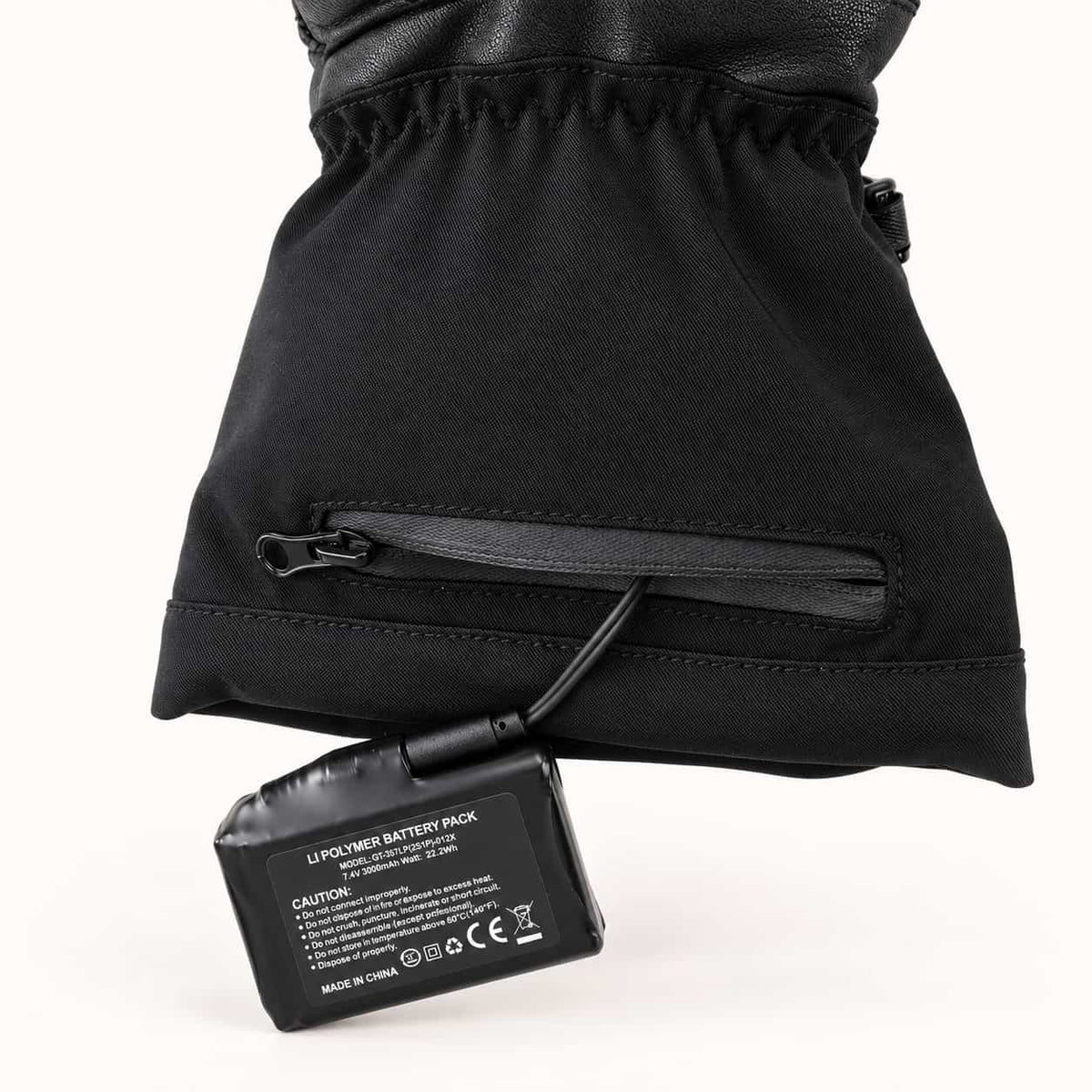 A 7.4V rechargeable battery connected to a Basalt heated motorcycle glove through its zippered cuff pocket.