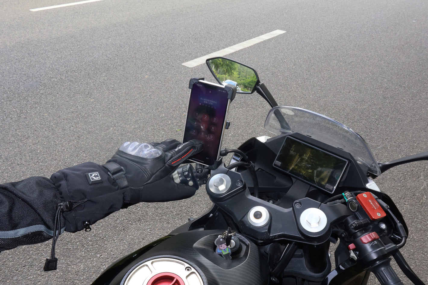 Rider using the touchscreen index finger of a Basalt heated motorcycle glove on a mounted smartphone