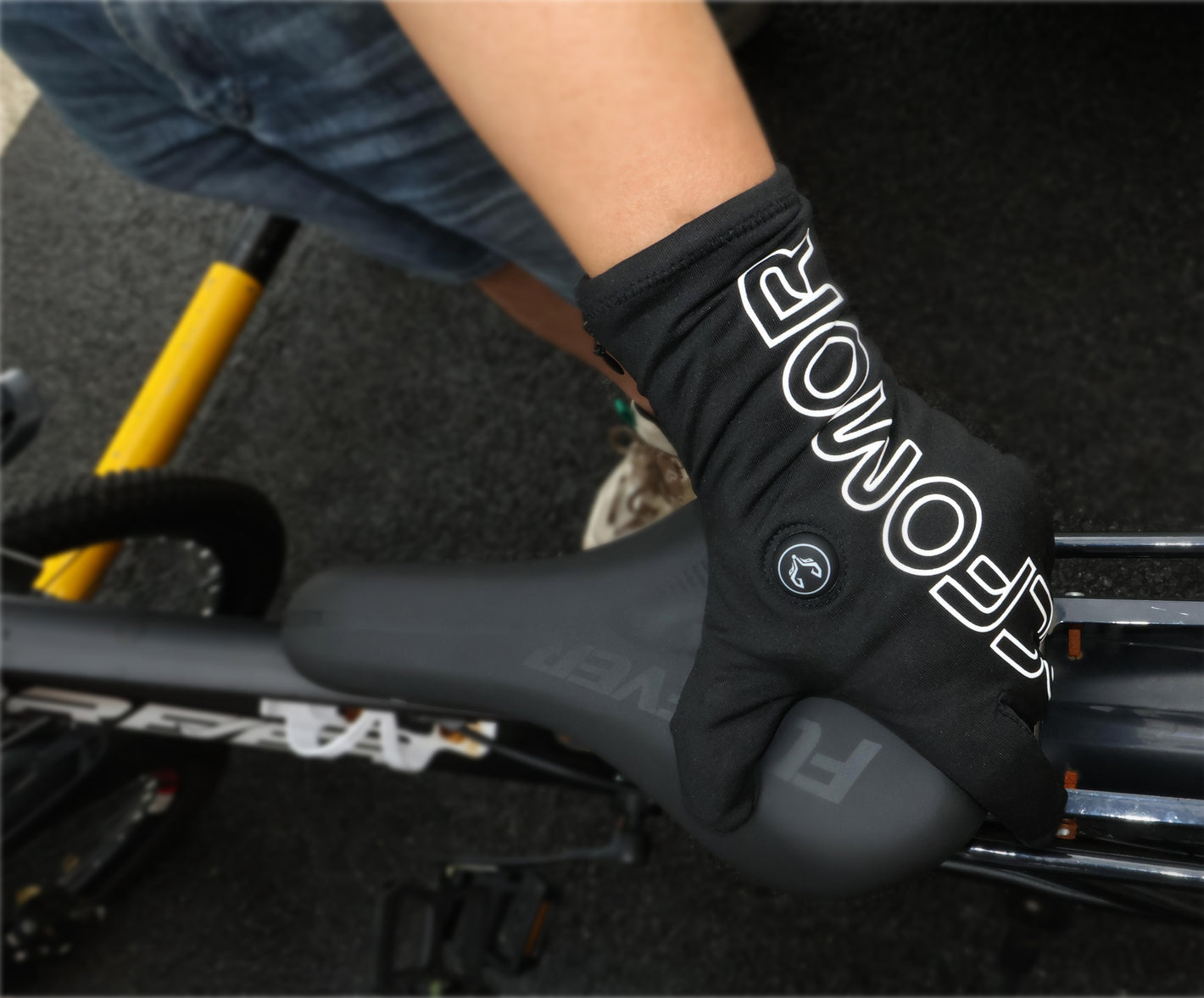 Feather heated glove in the earlier large-logo style holding a bicycle seat