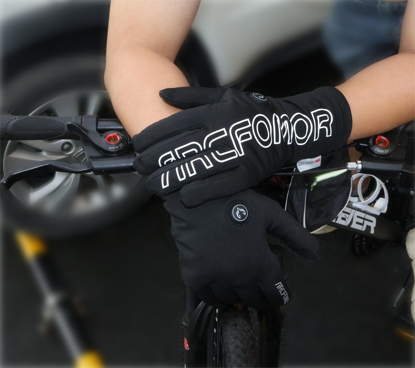 Feather heated gloves in the earlier large-logo style holding a cold-weather handlebar