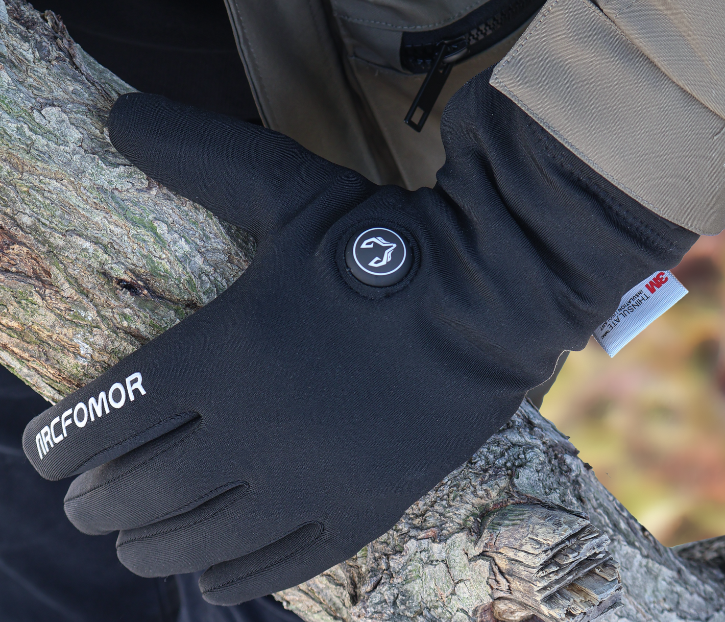 Feather slim-fit heated gloves worn outdoors beside a tree
