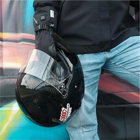 Person wearing Helm heated outdoor gloves while holding a motorcycle helmet before a casual cold-weather ride