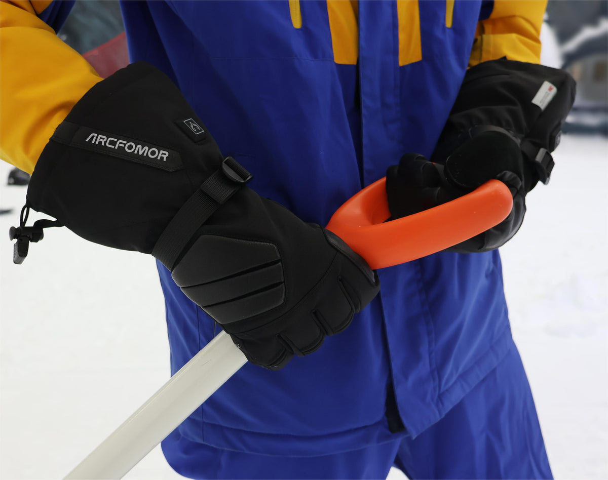 Person wearing black Helm heated outdoor gloves while shoveling snow