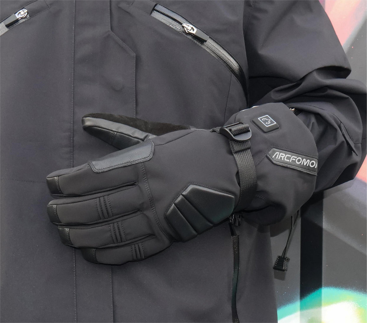 Person wearing black Helm heated outdoor gloves with long cuffs and adjustable wrist straps