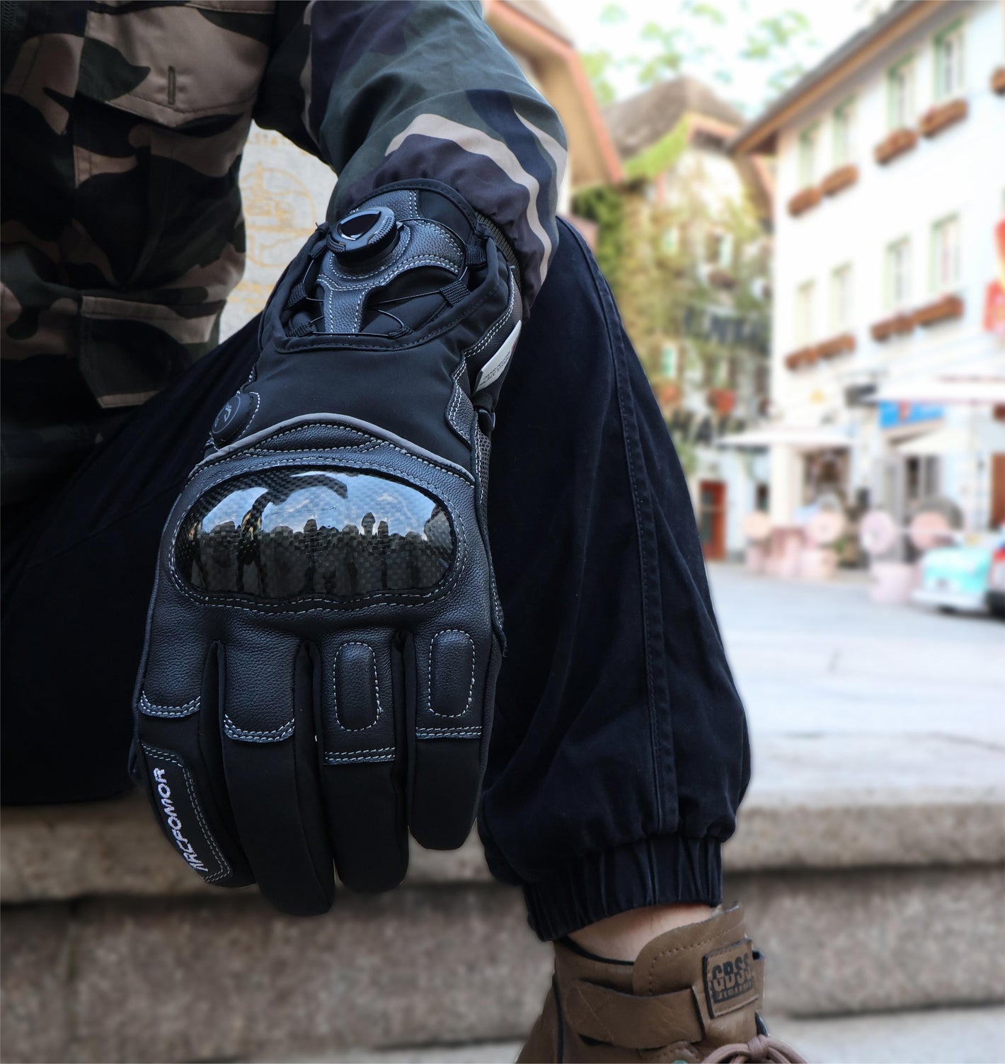 Onyx short-cuff heated motorcycle glove worn outdoors, showing the carbon-fiber knuckle shell and rotary-dial closure