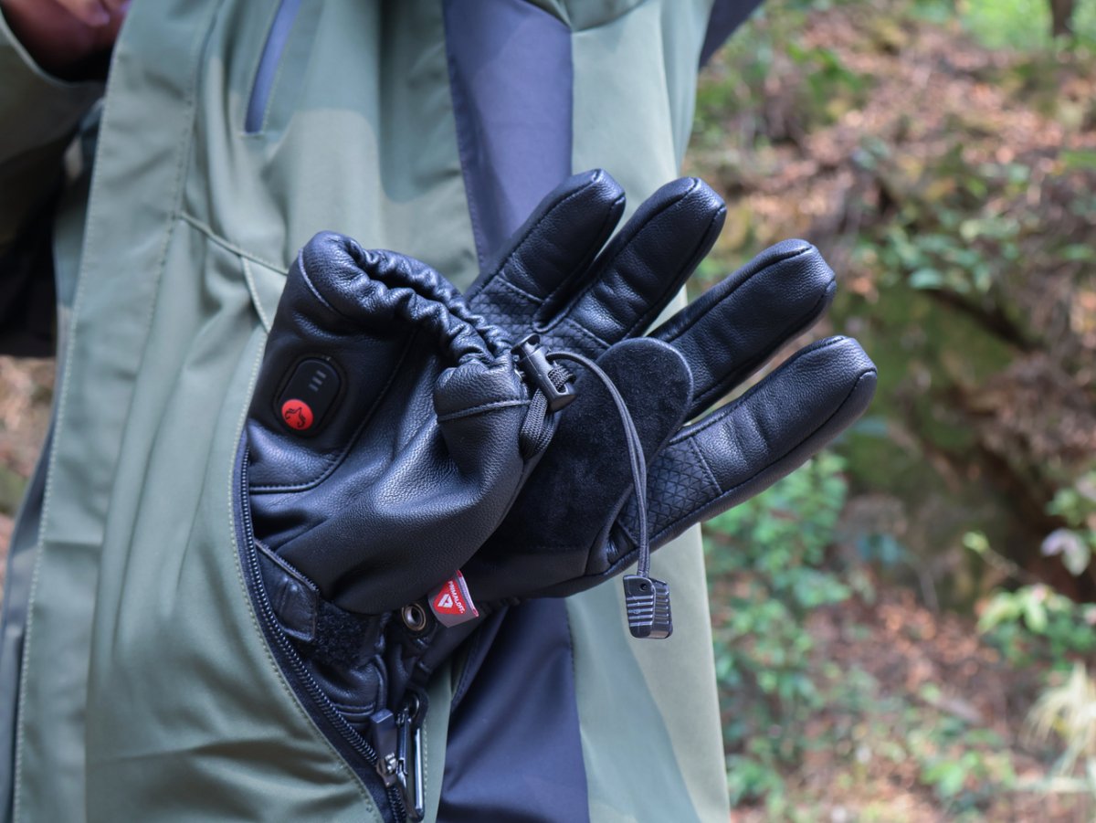 Person holding Polar Baron heated gloves with the drawcord cuff visible outdoors