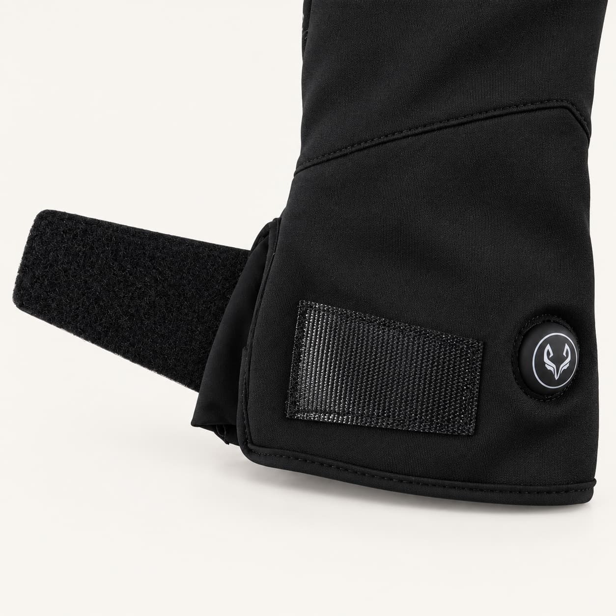 Open adjustable wrist strap and round heat control button on a Spider Silk heated glove.