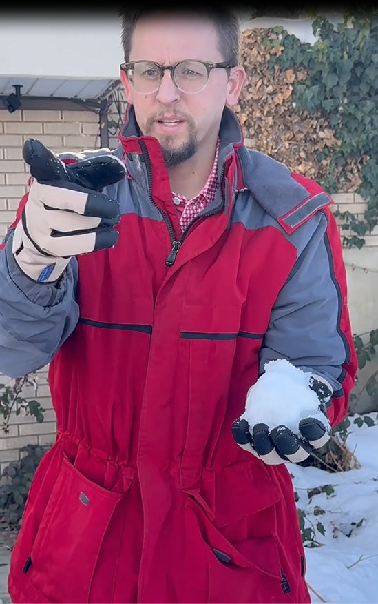 Man wearing Summit of Kunlun shell gloves while handling snow outdoors