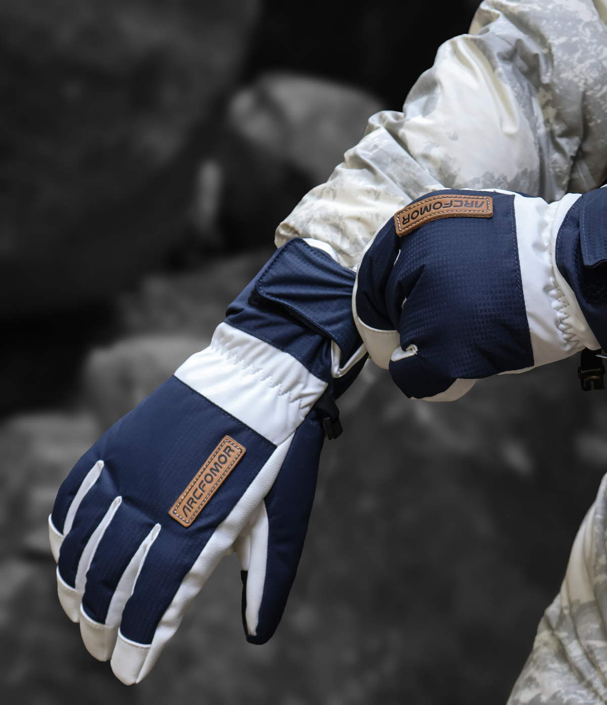 Close-up of white and navy Summit of Kunlun shell gloves being worn outdoors