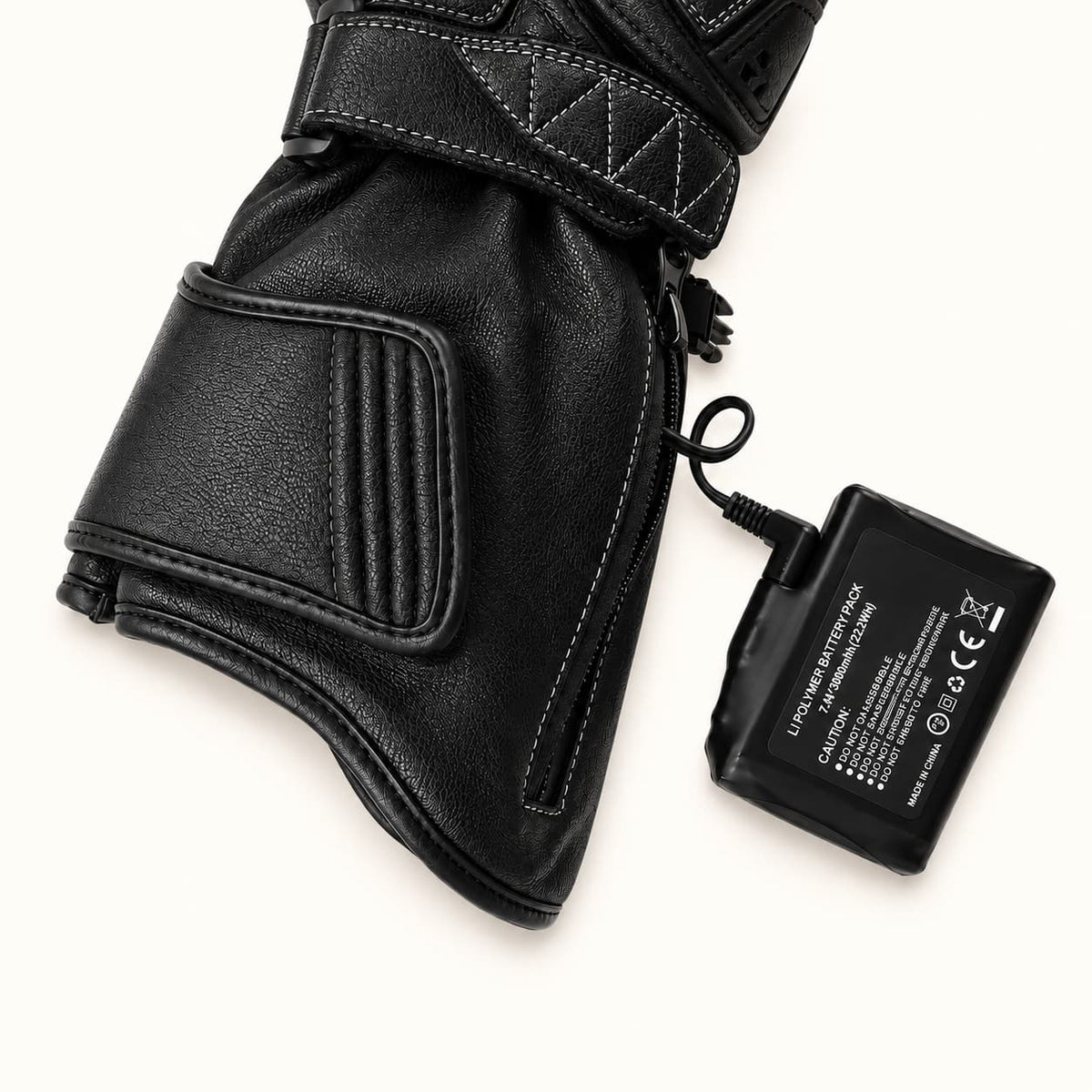 Tempest glove battery connected by a right-angle plug beside the zippered leather cuff pocket.