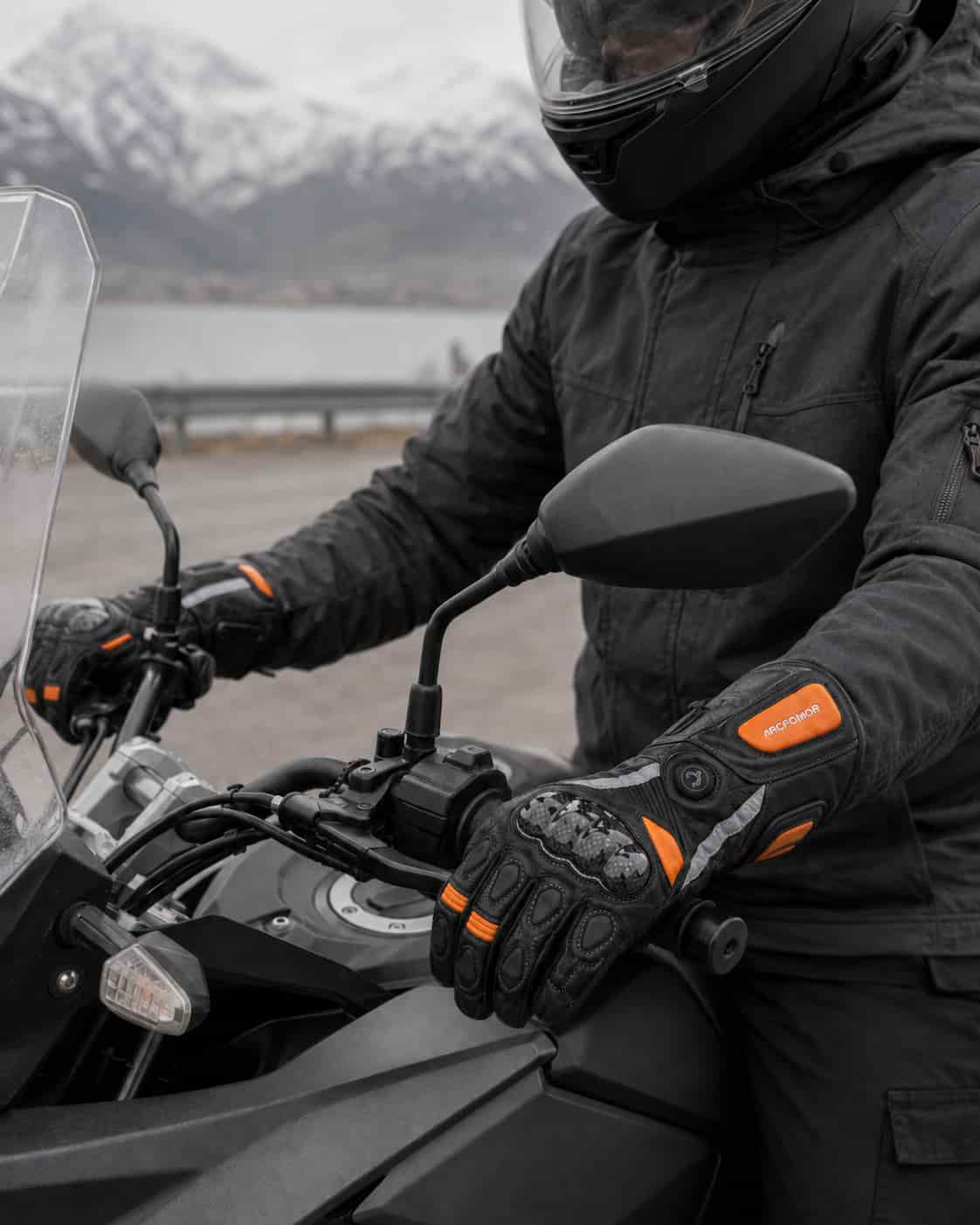 Rider wearing black and orange Tempest heated motorcycle gloves during a cold-weather touring stop