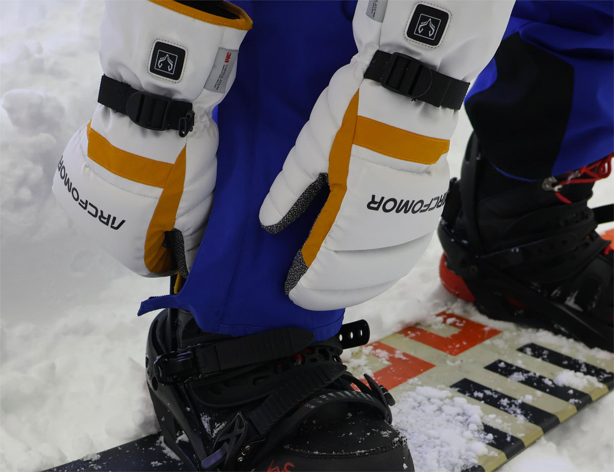 Snowboarder wearing Toboggan heated mittens while adjusting a snowboard binding