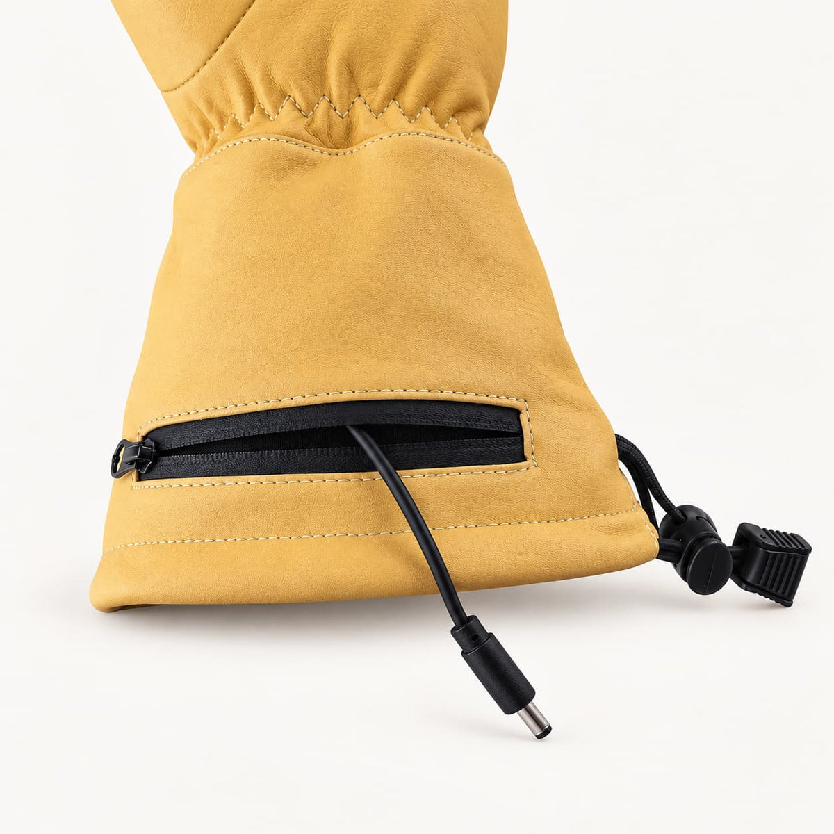 Open zippered cuff battery pocket on a yellow Vellum 2.0 glove, with the power cable and barrel connector visible.