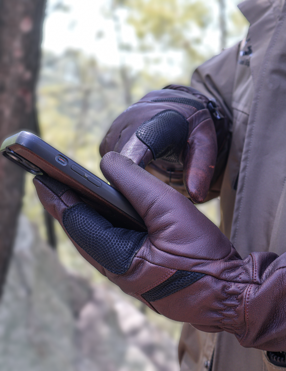 Using a smartphone outdoors while wearing brown Vellum heated gloves