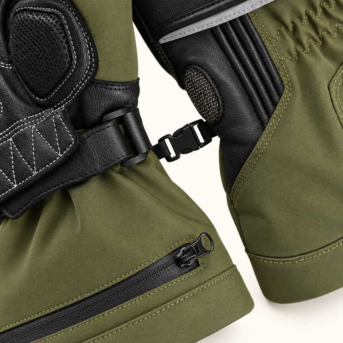 Close-up of the pairing clip joining two Vortex gloves, with olive fabric cuffs and black leather wrist panels.