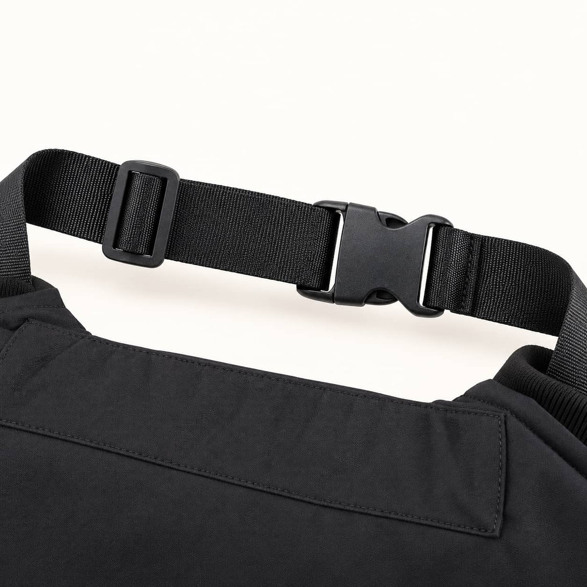 Close-up of the WarmHeart muff’s woven waist belt, showing its side-release buckle, adjustment slider and stitched attachment.