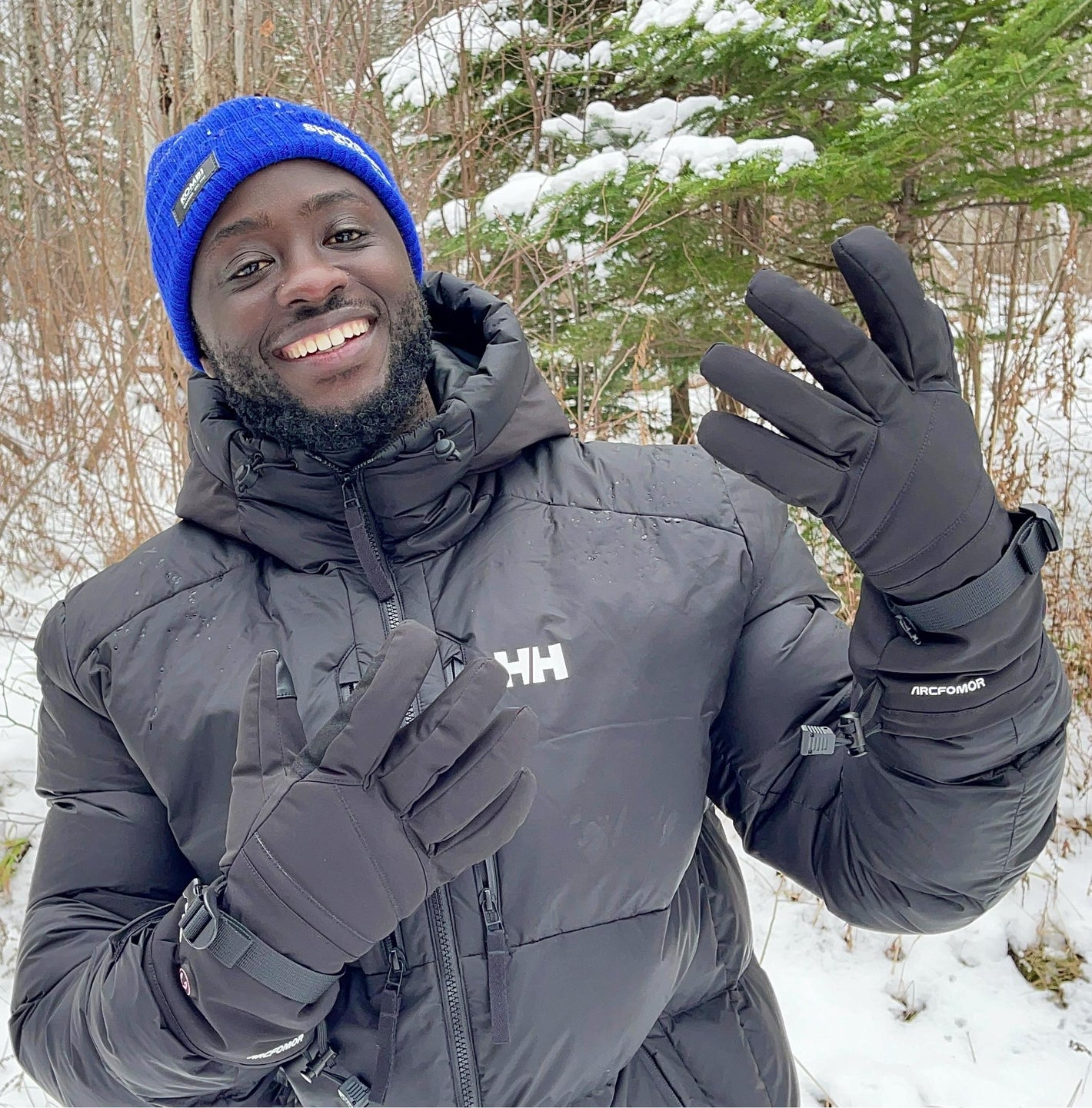 Man wearing black WinterGlow waterproof heated gloves during a snowy winter walk