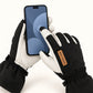Hands wearing black Yellowstone gloves holding a smartphone and tapping the screen with an index fingertip.