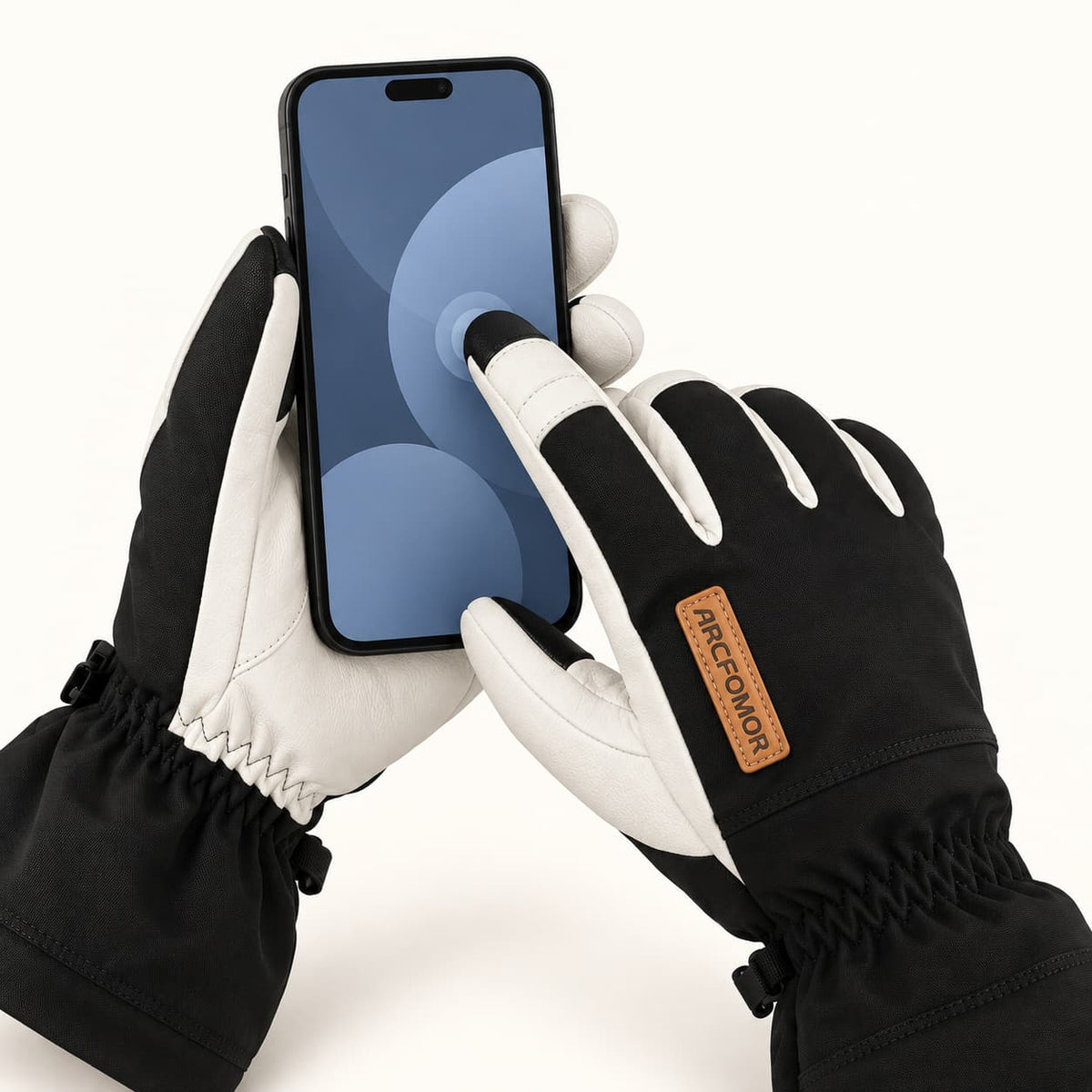 Hands wearing black Yellowstone gloves holding a smartphone and tapping the screen with an index fingertip.