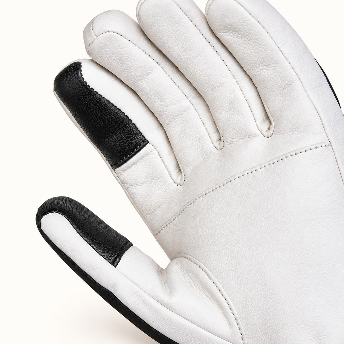 Close-up of a Yellowstone glove’s white leather palm, showing black touchscreen patches on the thumb and index fingertip.